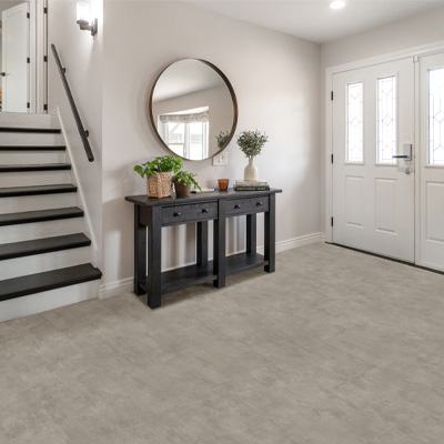 luxury vinyl tile flooring in entryway with dark wooden entry table and large mirror